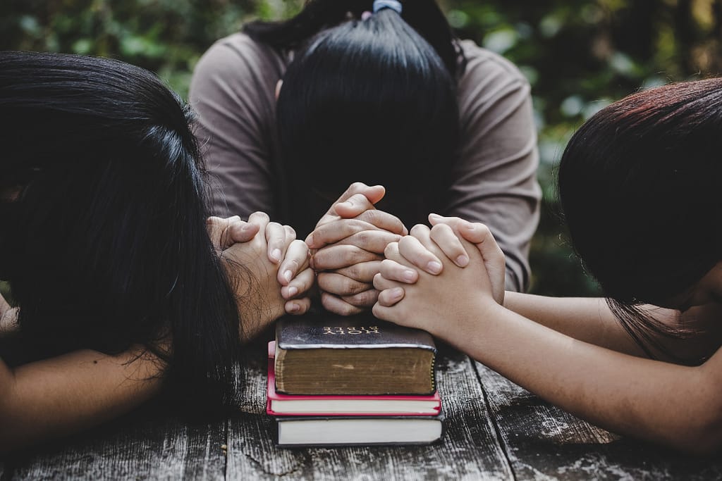 Three women praying for each other.